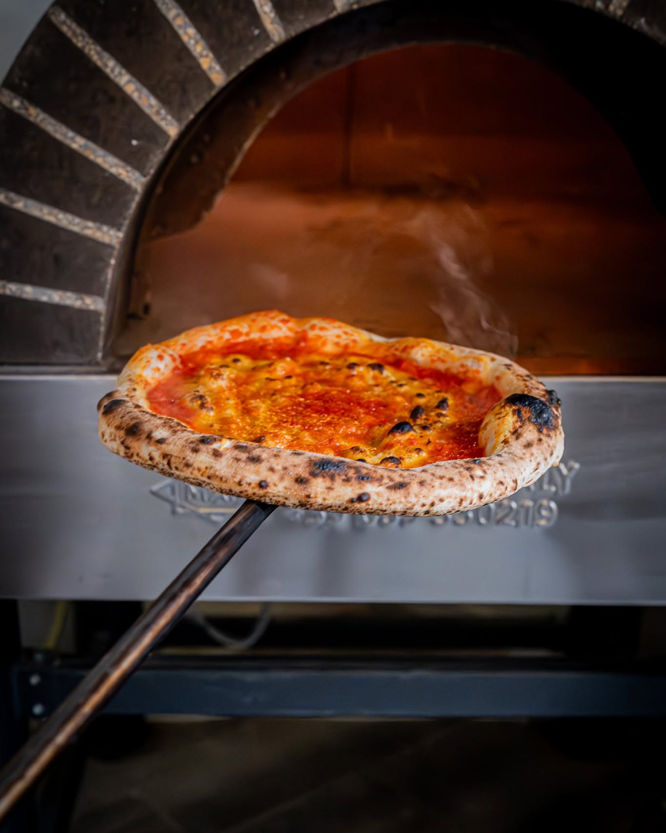Pizza napolitana saliendo del horno de leña